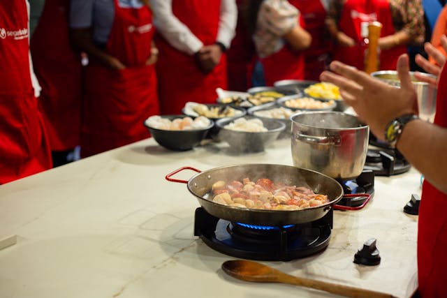 Cooking & Gourmet - team in cucina con chef, pentole fumanti e tagliere di verdure